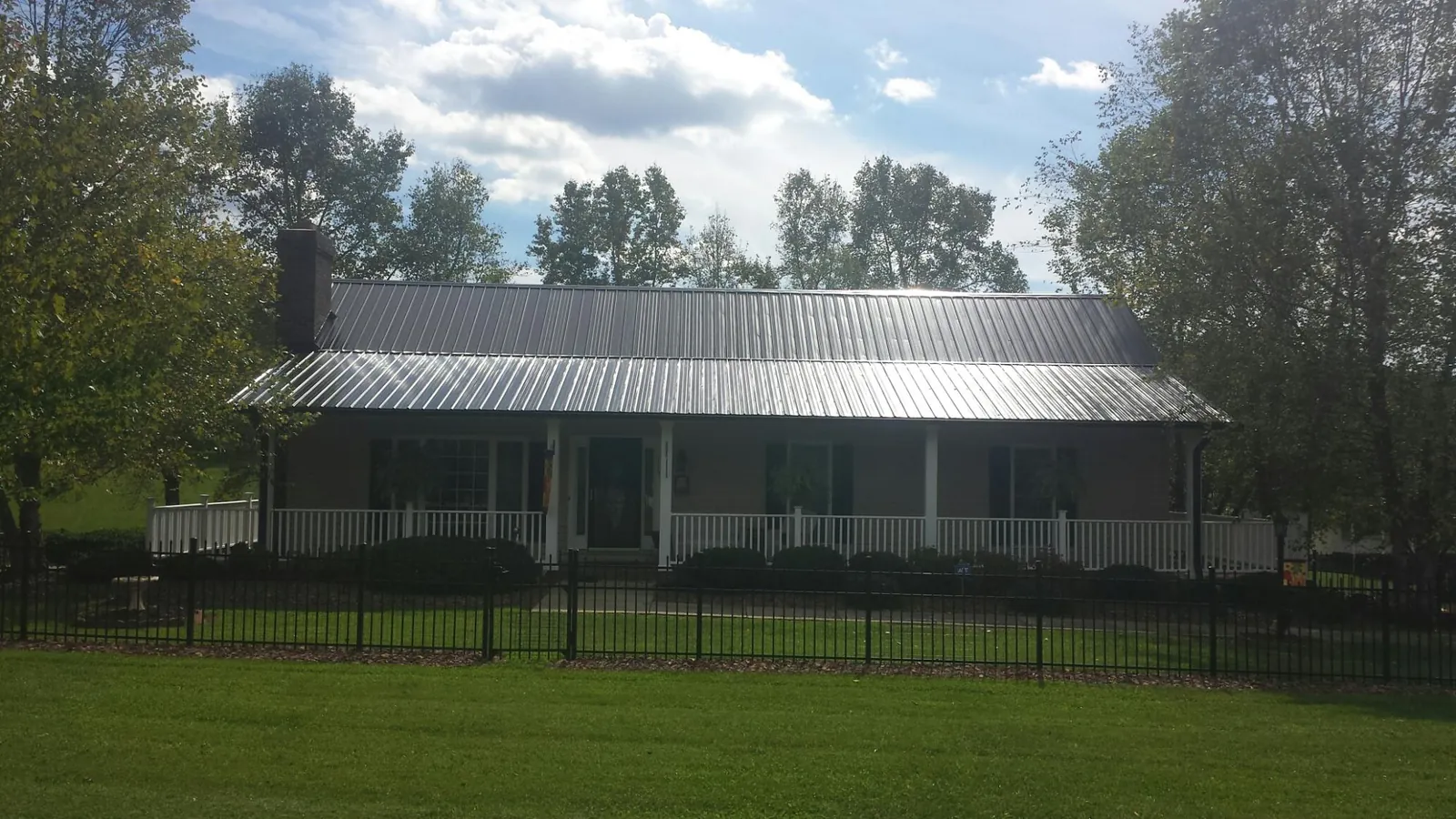 Gray metal roof on a brick ranch with a full width front porch — Gutter Guard Installation work by our crew in Martinsville