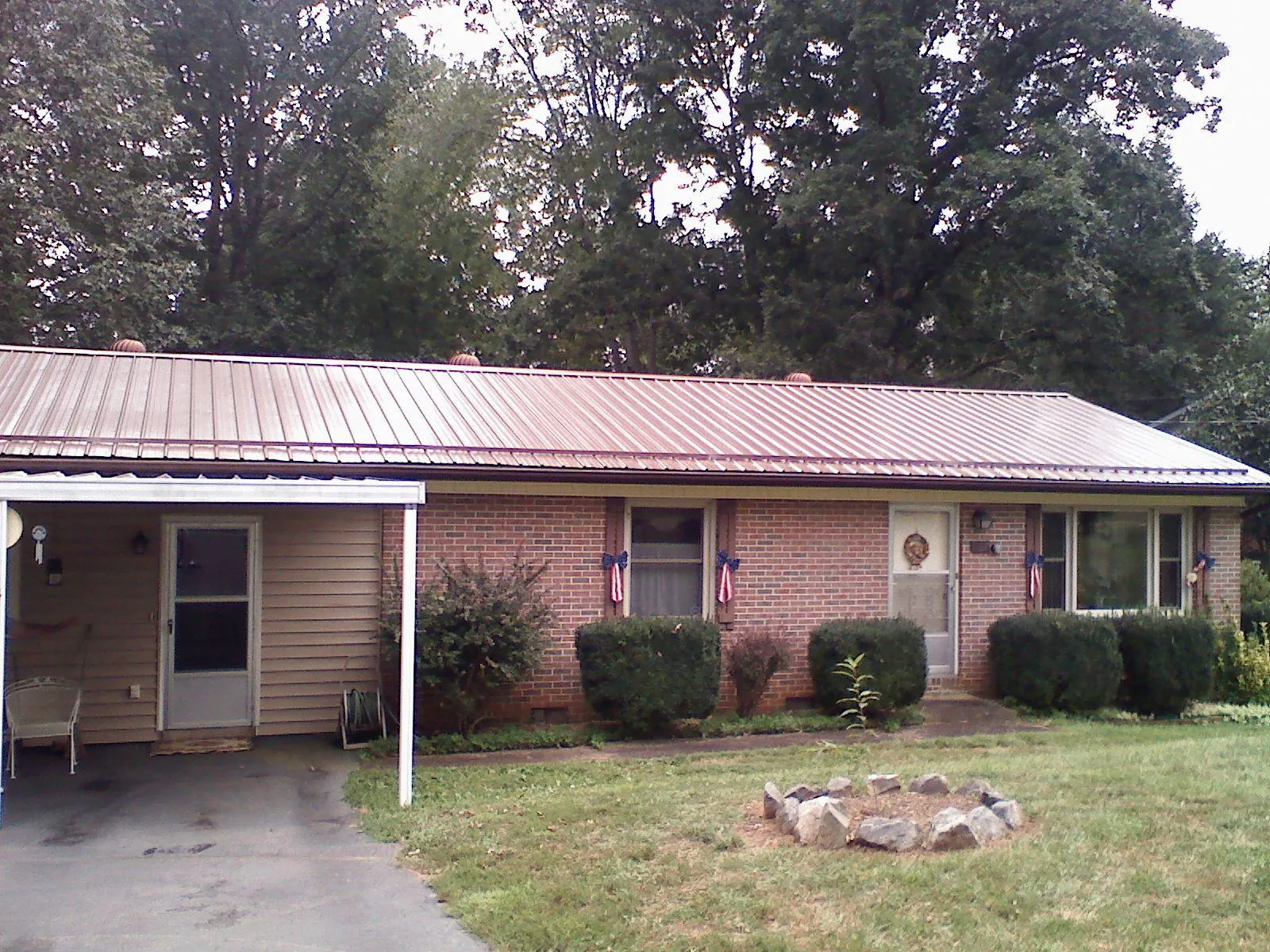 Bronze metal roof and carport on a brick ranch home — Roof Repair work by our crew in Martinsville